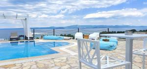 a beach with a pool, chairs, and a swimming pool at Bungalow White Tennis Apartments & Suites in Pefkochori