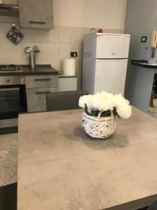 een vaas met bloemen op een tafel in een keuken bij Appartamento sulla piazza 90 m dal mare in Anzio