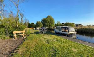 a bench next to a river with a boat at Boat Stoer kamperen op het water - niet om mee te varen - lees hostprofiel-read host profile in Jutrijp