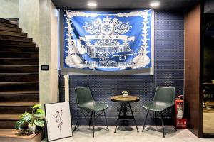 a table and four chairs in front of a wall with a banner at Holo Hotel Tainan in Tainan