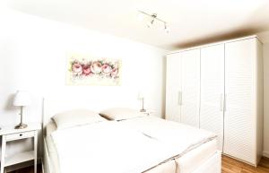 een witte slaapkamer met een bed en een schilderij van bloemen bij Gästehaus Sam in Bad Sassendorf
