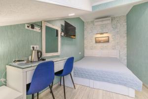 a small bedroom with a bed and a desk and chairs at Hotel Nicolas in Tbilisi City