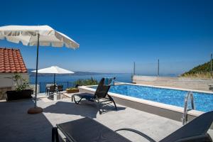 einen Pool mit einem Stuhl und einem Sonnenschirm in der Unterkunft Villa Panorama in Omiš