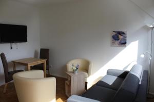 ein Wohnzimmer mit einem Sofa, Stühlen und einem TV in der Unterkunft Bauernhof Sesterhenn in Leichlingen