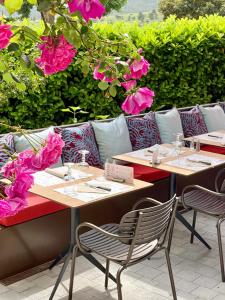 Duas mesas com cadeiras e flores cor-de-rosa num pátio em Hotel Le Provence - Restaurant Le Styx em La Palud sur Verdon