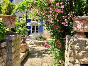 a garden with pink flowers and a stone wall at le vieux pont in Carpentras
