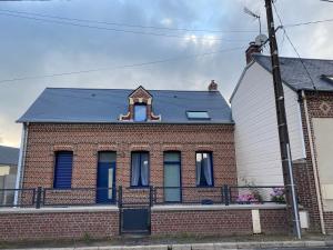 ein Backsteinhaus mit blauen Fenstern und einem Dach in der Unterkunft Gîte les Retrouvailles in Saint-Quentin-Lamotte-Croix-au-Bailly