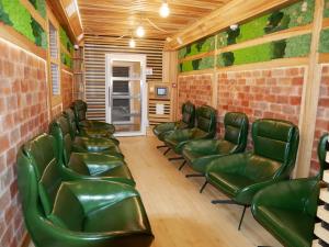 una sala de espera con sillas de cuero verde y una pared de ladrillo en Holistic, en Solec-Zdrój