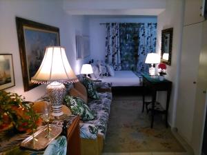 a living room with a bed and a couch with a lamp at Metropolis studio in Corfu
