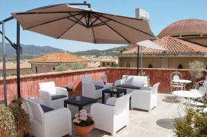a patio with white chairs and an umbrella at Hotel Sa Cralla Villasimius in Villasimius