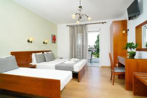 Habitación de hotel con 2 camas y escritorio en Antigone Hotel, en Limenas