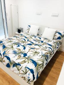 uma cama com um edredão e almofadas azuis e brancas em Grand T1 Moderne Jardin près de CDG em Le Thillay