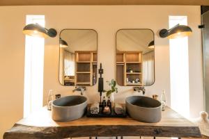 two sinks in a bathroom with two mirrors at Mavela Game Lodge in Manyoni Private Game Reserve