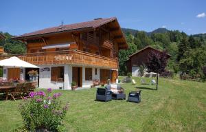 a house with a yard with chairs and a table at La Passerelle chambre au calme proche la Clusaz et Grand Bornand in Saint-Jean-de-Sixt