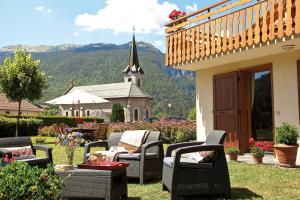 a patio with chairs and a church in the background at La Passerelle chambre au calme proche la Clusaz et Grand Bornand in Saint-Jean-de-Sixt