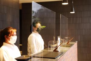 a woman wearing a face mask in front of a mirror at LOF HOTEL Shimbashi in Tokyo