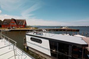 Ein Boot liegt an einer Anlegestelle mit einem Haus. in der Unterkunft Hausboote und Fewo Vieregge in Vieregge