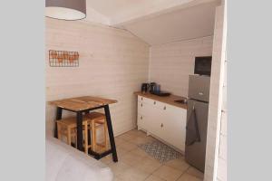 una pequeña cocina con mesa y nevera en Maisonnette en pierre indépendante de 20 m2 en Saint-Cirgues-sur-Couze