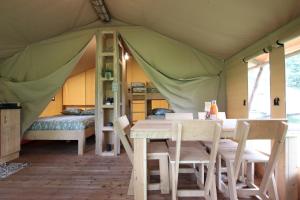 uma sala de jantar numa tenda com uma mesa e cadeiras em TENTE SAFARI Lodge FERME CARRIQUE em Tardets-Sorholus