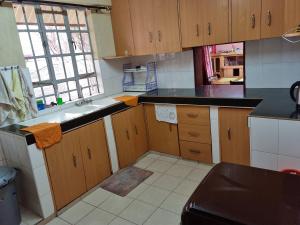 a kitchen with wooden cabinets and a black counter top at Weavers Haven in Naivasha