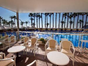 a pool with tables and chairs and palm trees at Hotel Servigroup Papa Luna in Peniscola