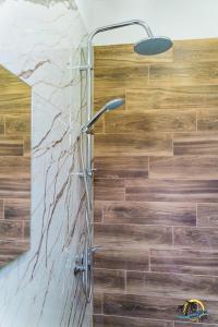 a shower in a bathroom with a wooden wall at Gradina Holiday in Sozopol