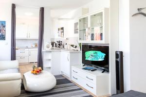 ein Wohnzimmer mit weißen Schränken und einem Flachbild-TV in der Unterkunft Auszeit Apartment DOWNTOWN im Herzen der Innenstadt - am Hafen und am Bodenseeradweg - schnelles Internet, für bis zu 2 Personen in Friedrichshafen