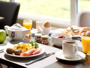 uma mesa com comida para o pequeno almoço e café nela em ACHAT Hotel Zwickau em Zwickau