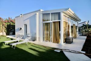 a house with a lawn with two white chairs on it at VILLA MARE BLUE SR Nuovissima Villa 150m dal mare adatta a bambini in Terrauzza