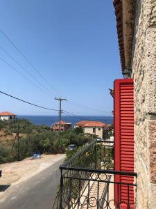 a red shutter on a balcony with a view of the ocean at Hotel Esperides in Kardamili