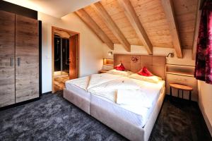 a bedroom with a large white bed with red pillows at Hotel Garni Stefanie in Ischgl