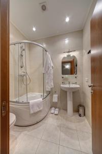 a bathroom with a tub shower and a sink at Sonata on Fontanka in Saint Petersburg