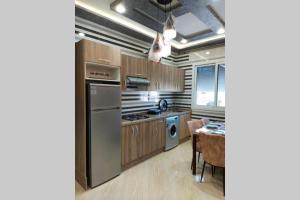 uma cozinha com um frigorífico de aço inoxidável e uma mesa em Aprt 12 nouvelle résidence 5 min la plage em Martil