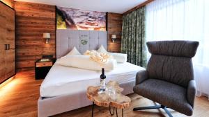 a bedroom with a large bed and a chair at Hotel Garni Stefanie in Ischgl