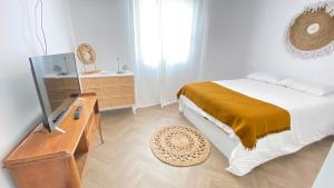 a bedroom with a bed and a dresser with a television at Can-Carma El Conserje in Denia
