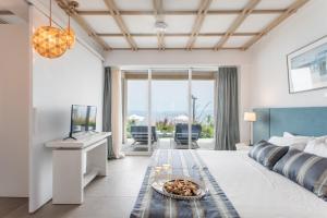 a room with a bed and a tv and a table at Rigas Boutique Hotel & Spa in Afitos