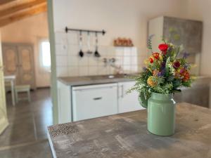 a vase with flowers on a table in a kitchen at Ibolya Apartman in Csisztapuszta