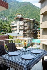 una mesa en un balcón con vistas a un edificio en Hotel Turkish Cottage, en Dharamshala