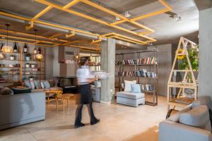 a person walking through a living room with bookshelves at Rigas Boutique Hotel & Spa in Afitos