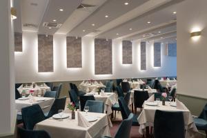 um restaurante com mesas brancas e cadeiras azuis em Hotel Fenyõ em Miercurea-Ciuc