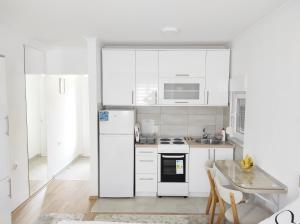een witte keuken met witte apparatuur en een tafel bij Apartment SUNSET in Trebinje
