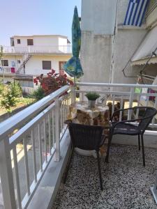 stół i krzesła na balkonie z parasolem w obiekcie Little Beauty - HappyHostGr - in Platamonas w mieście Platamonas