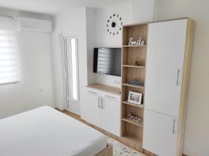 een witte kamer met een bed en een televisie bij Apartment SUNSET in Trebinje