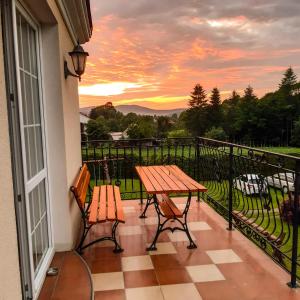 a table and chairs on a balcony with a sunset at Willa Kamieniec in Polańczyk