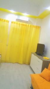 a room with a yellow curtain and a tv at Monolocale Marinaro in Peschici