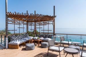 a deck with chairs and tables and a pergola at Rigas Boutique Hotel & Spa in Afitos