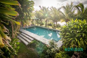 a swimming pool in a garden with palm trees at Horisun in Belle Mare