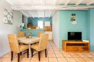 a dining room with a table and chairs and a television at La Bastide de l Etang in LʼIsle-sur-la-Sorgue