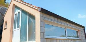 a house with a large window on the side of it at Laura Studio Apartman in Mlini +2 photos