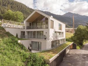 una casa blanca en una colina con una montaña en Omaela Apartments en Sankt Anton am Arlberg